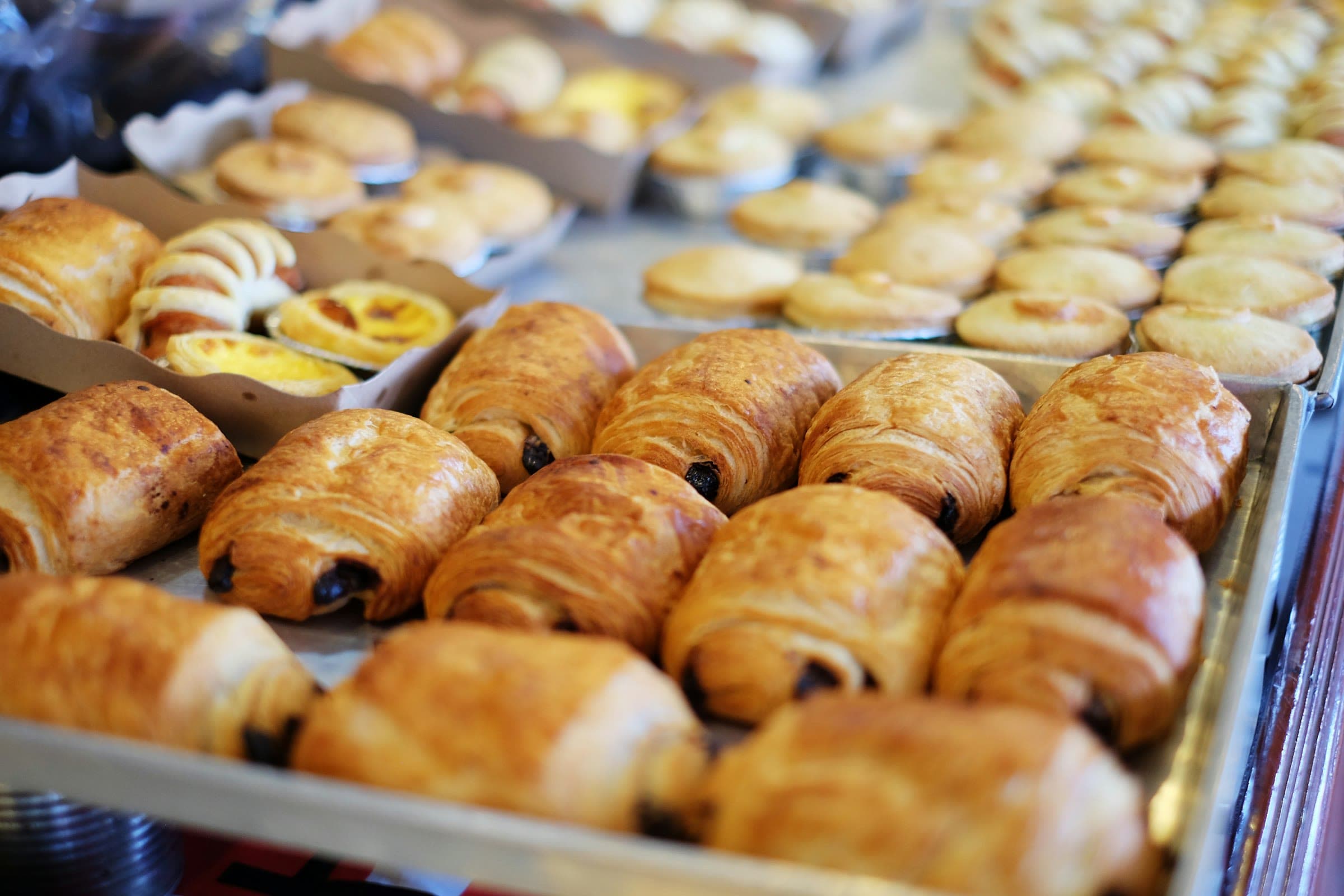 Viennoiseries et pâtisseries alignées sur des plaques